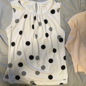 Sleeveless polka dot blouse.